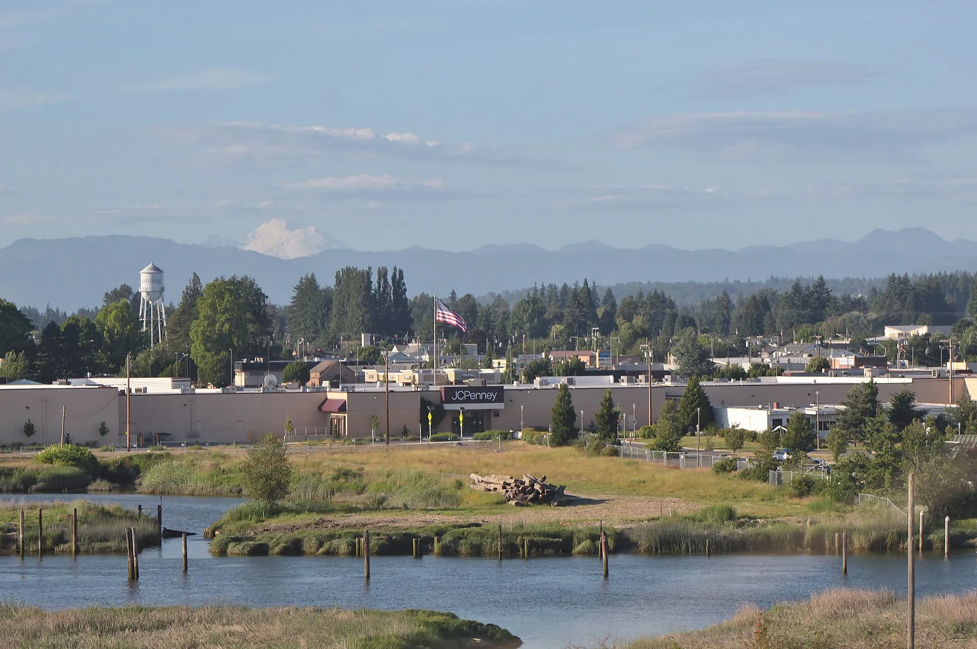 Marysville seen across a slough from Interstate 5, with its water tower and the Cascades behind